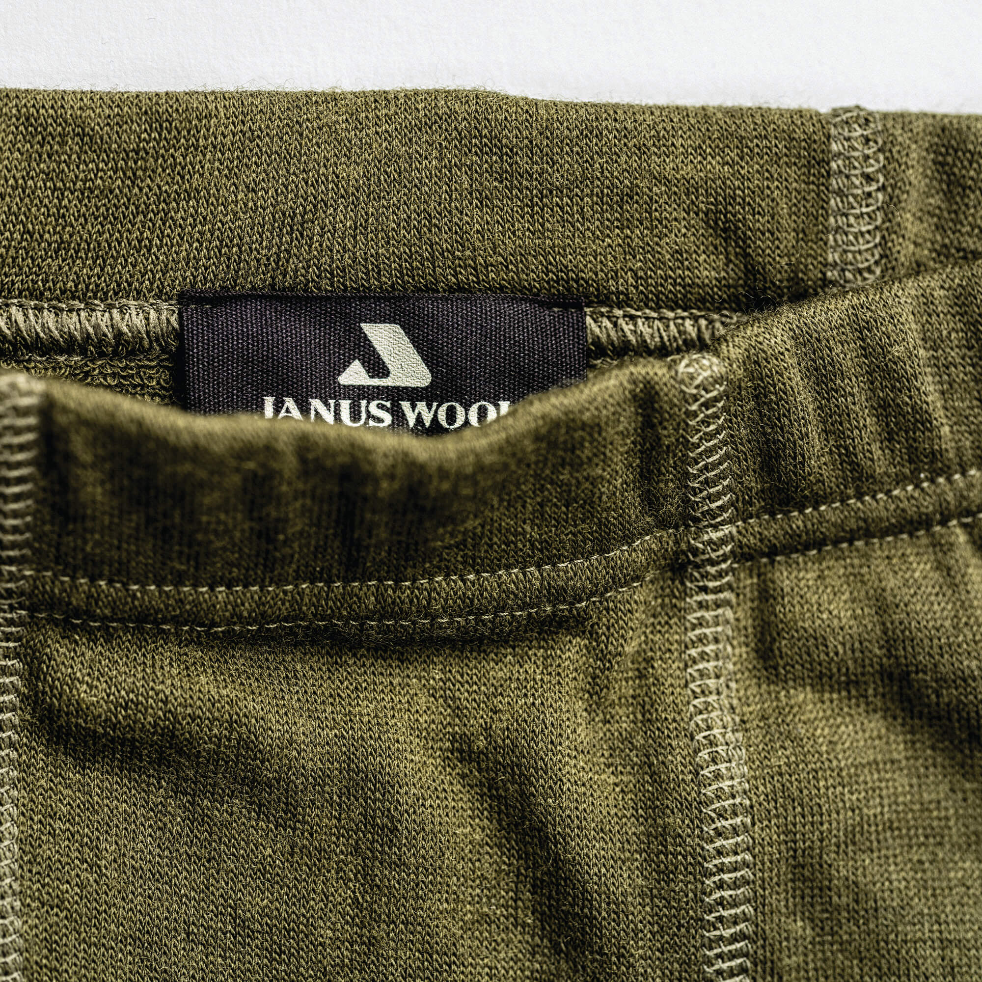 Close-up of green leggings in merino with Janus Wool logo on the waistband.