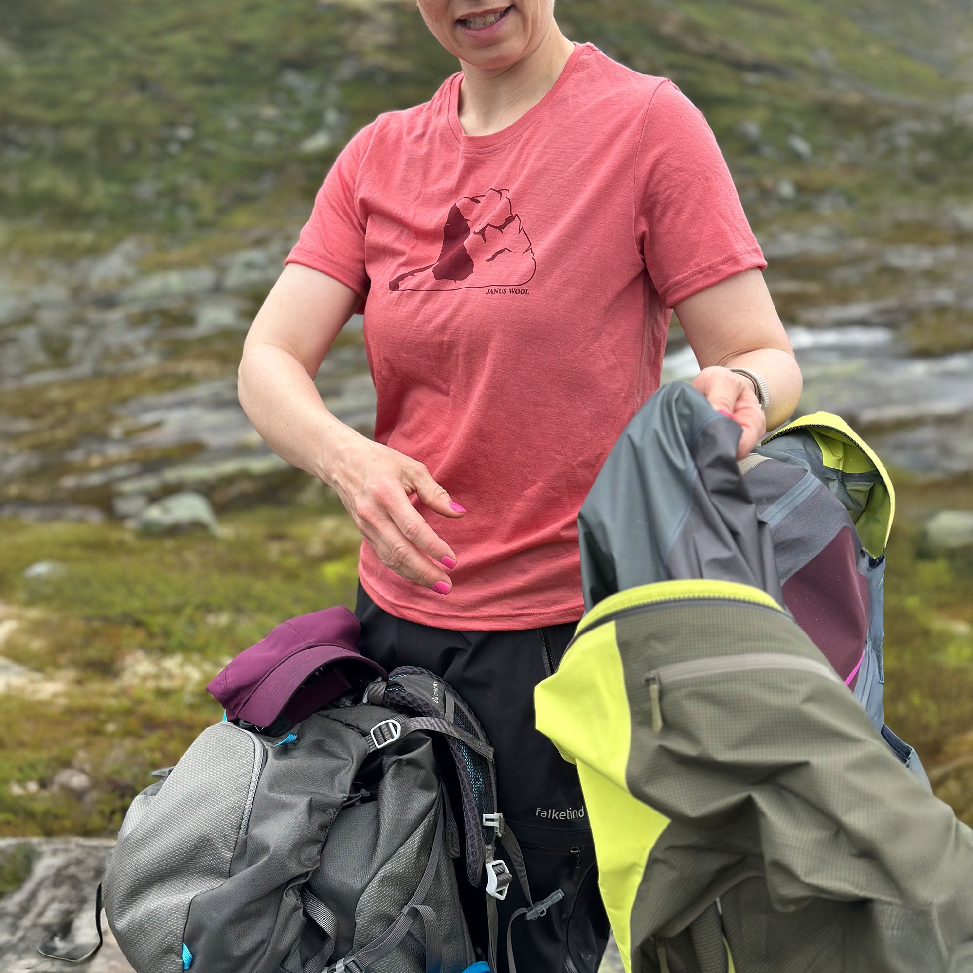 Person in Janus merino pink shirt with hiking gear in a mountainous area