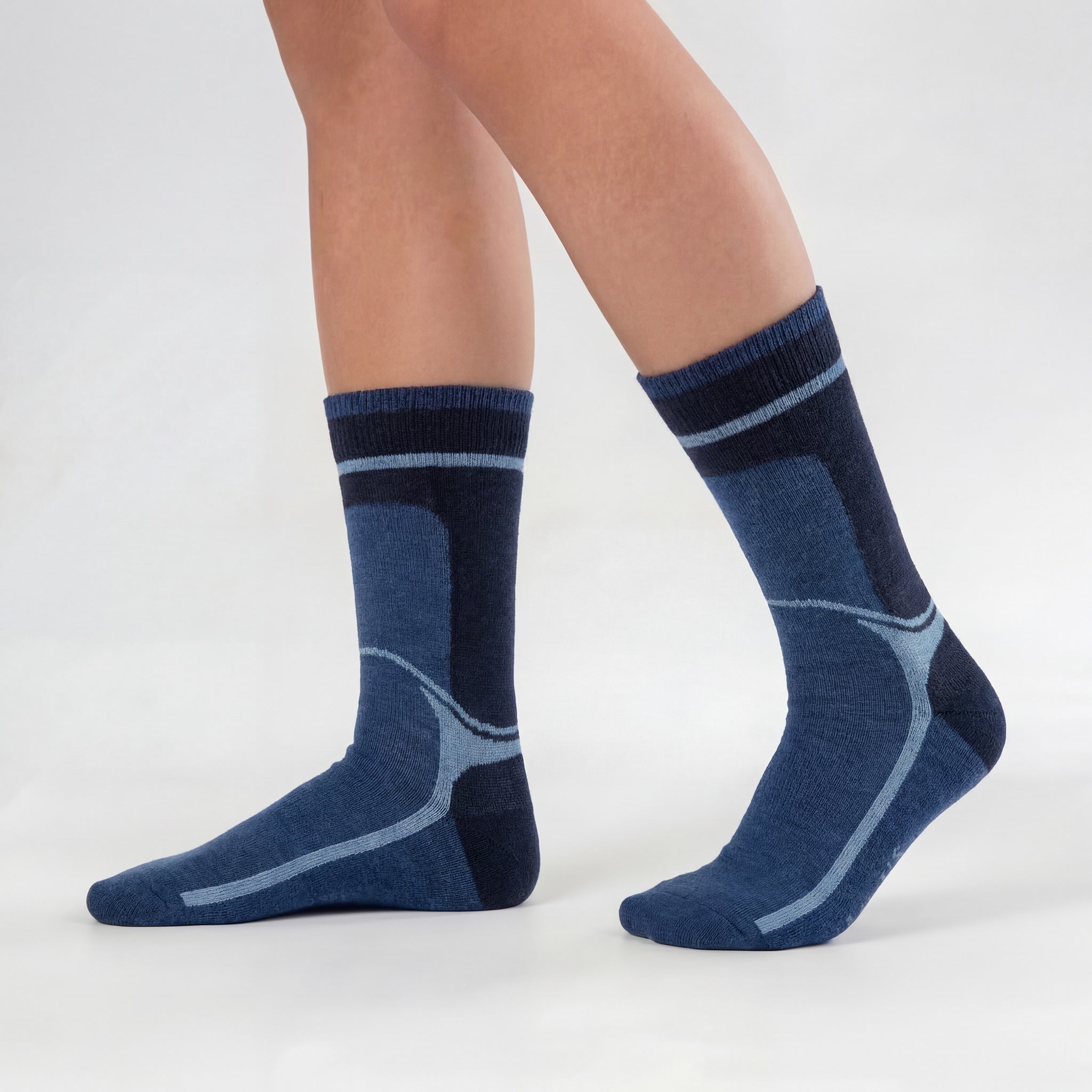 A person wearing Janusull blue wool socks with geometric patterns stands on a light gray surface, one foot flat and the other heel lifted. The mid-calf socks offer comfort and style.