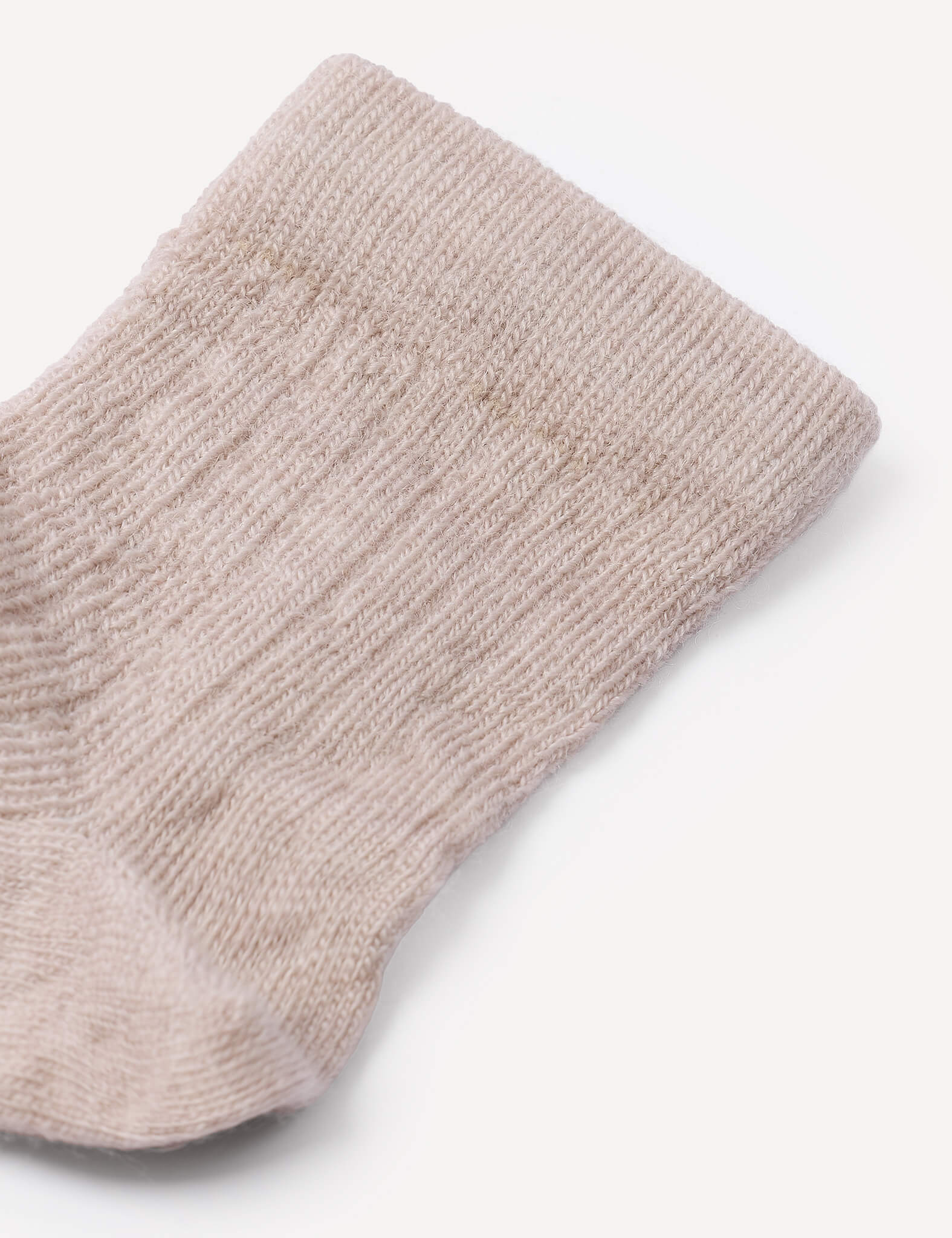 A close-up of the top portion of the beige, ribbed knit Socks – Merino Baby Light against a plain white background highlights these breathable baby socks.