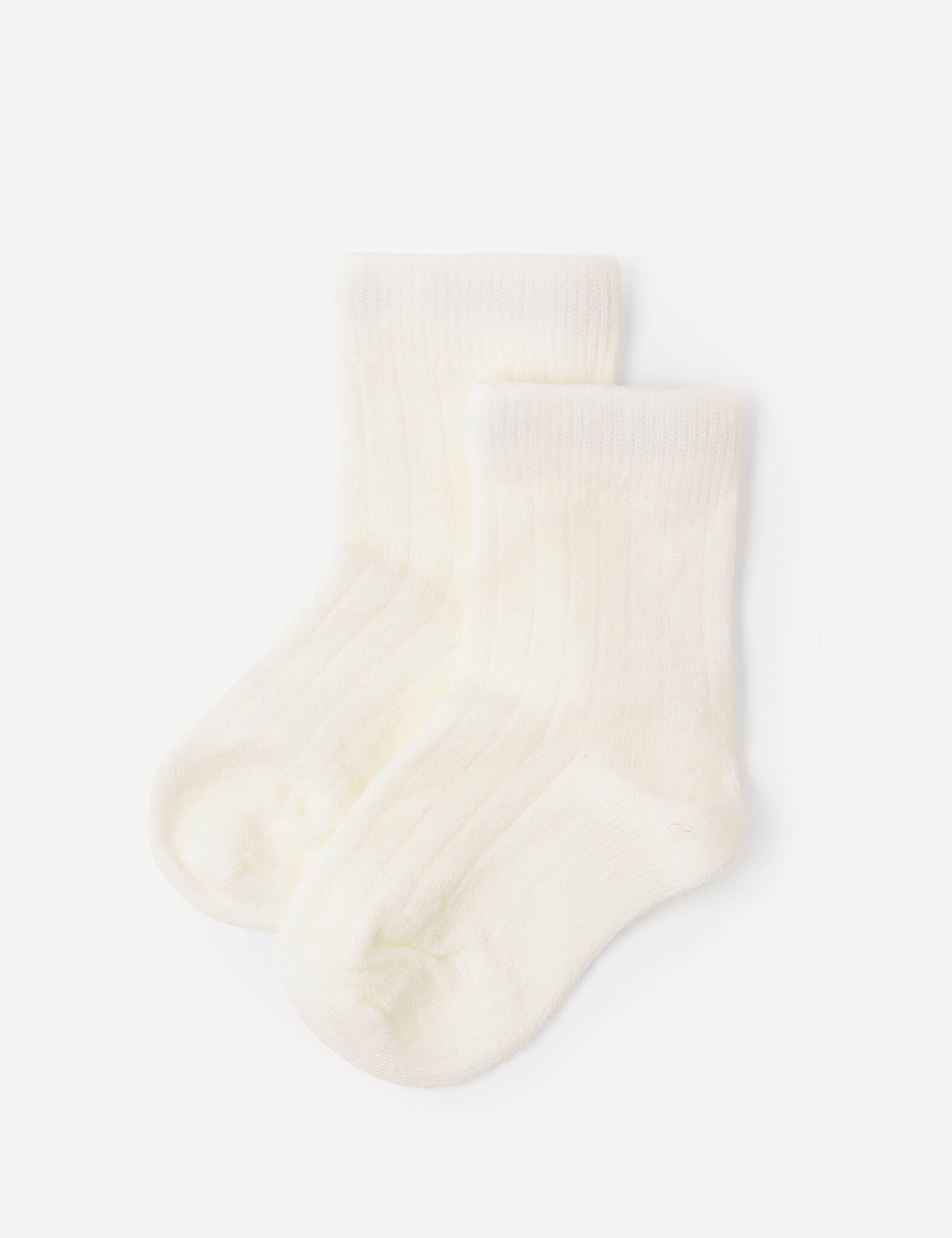 A pair of Socks – Merino Baby Light in the Marshmallow color, featuring a soft, ribbed texture, is laid flat on a white background. These breathable merino baby socks provide gentle comfort for little feet.