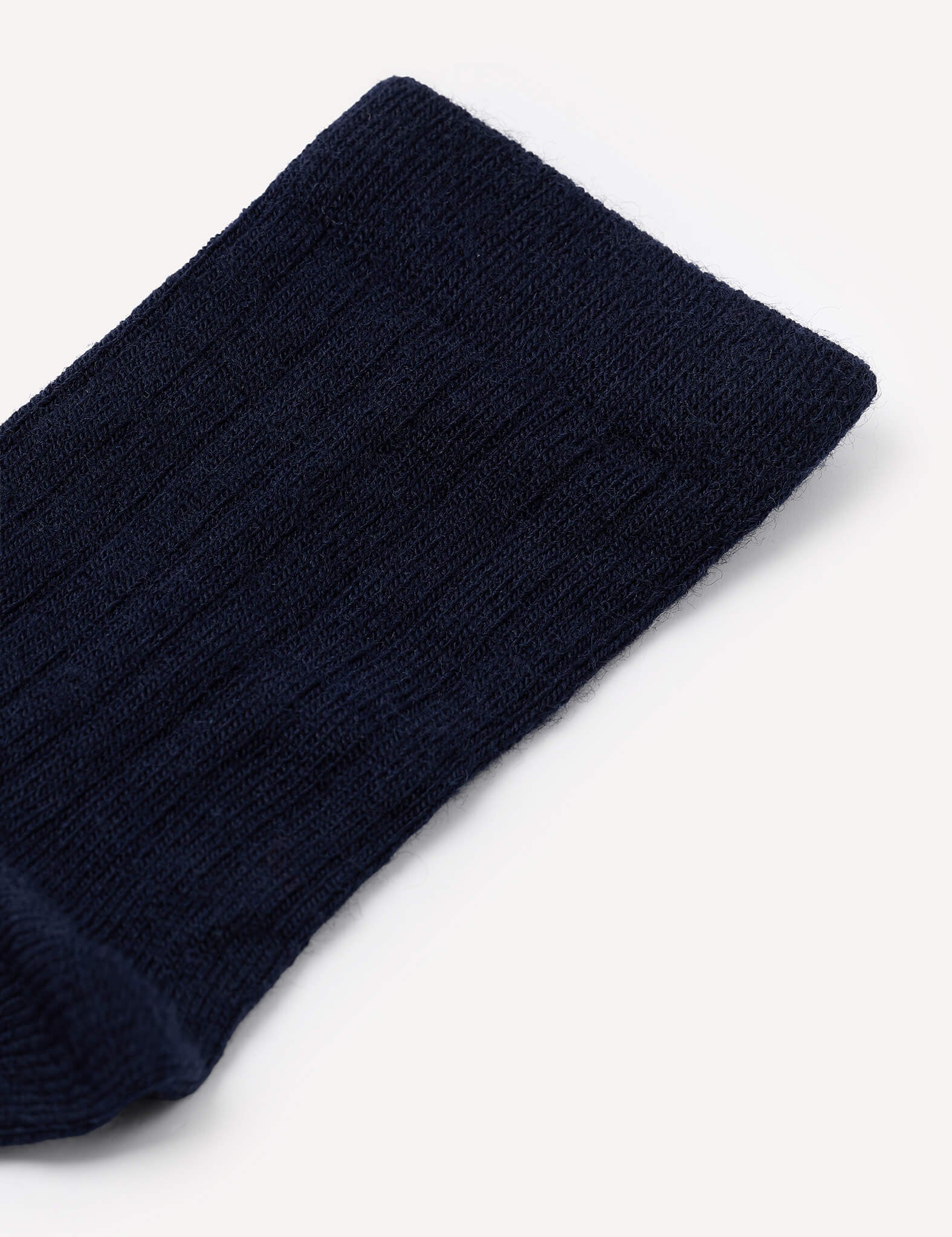Close-up of the upper section of a navy blue, ribbed Daily Socks – Merino Kids sock against a plain white background.