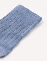 A close-up of a single light blue Daily Socks – Merino Kids thin wool sock with a ribbed knit texture, displayed on a plain white background.