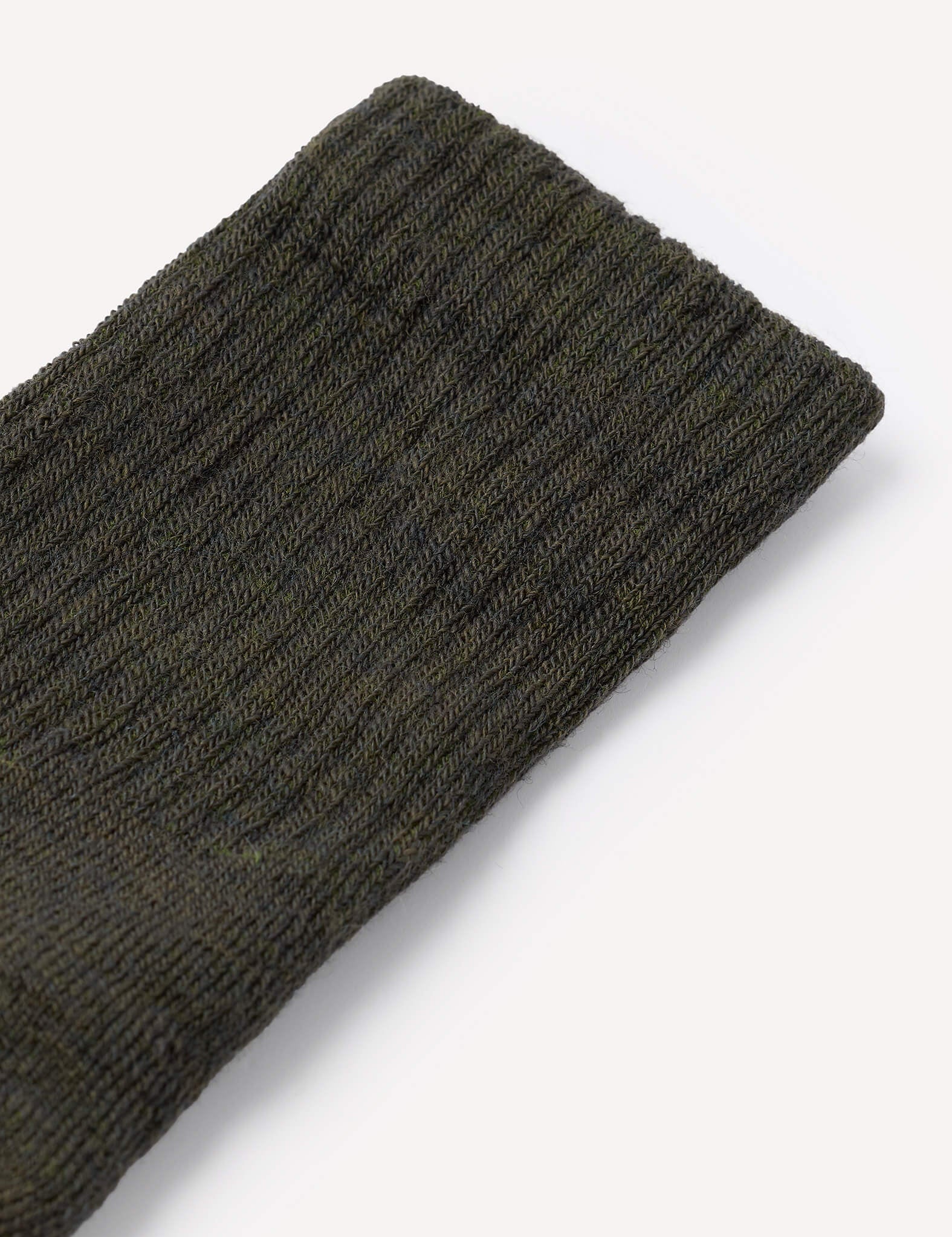 A close-up of a dark green, ribbed knit fabric—likely the cuff of the Terry Socks – Merino Kids—shown on a plain white background.