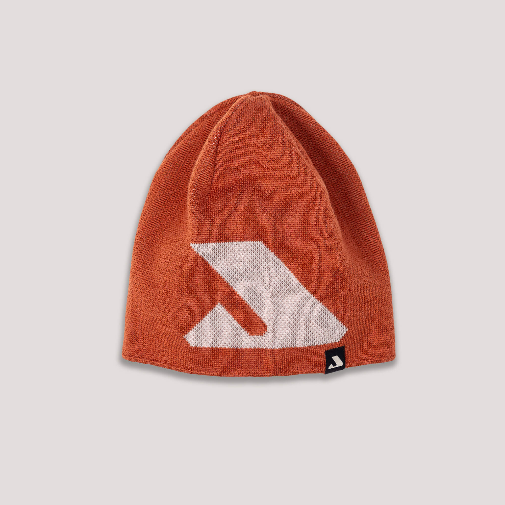 The Beanie – Logo in Mecca Orange features a large white geometric logo on the front and a small black logo tag at the bottom, providing warmth and breathability. Displayed on a light background.