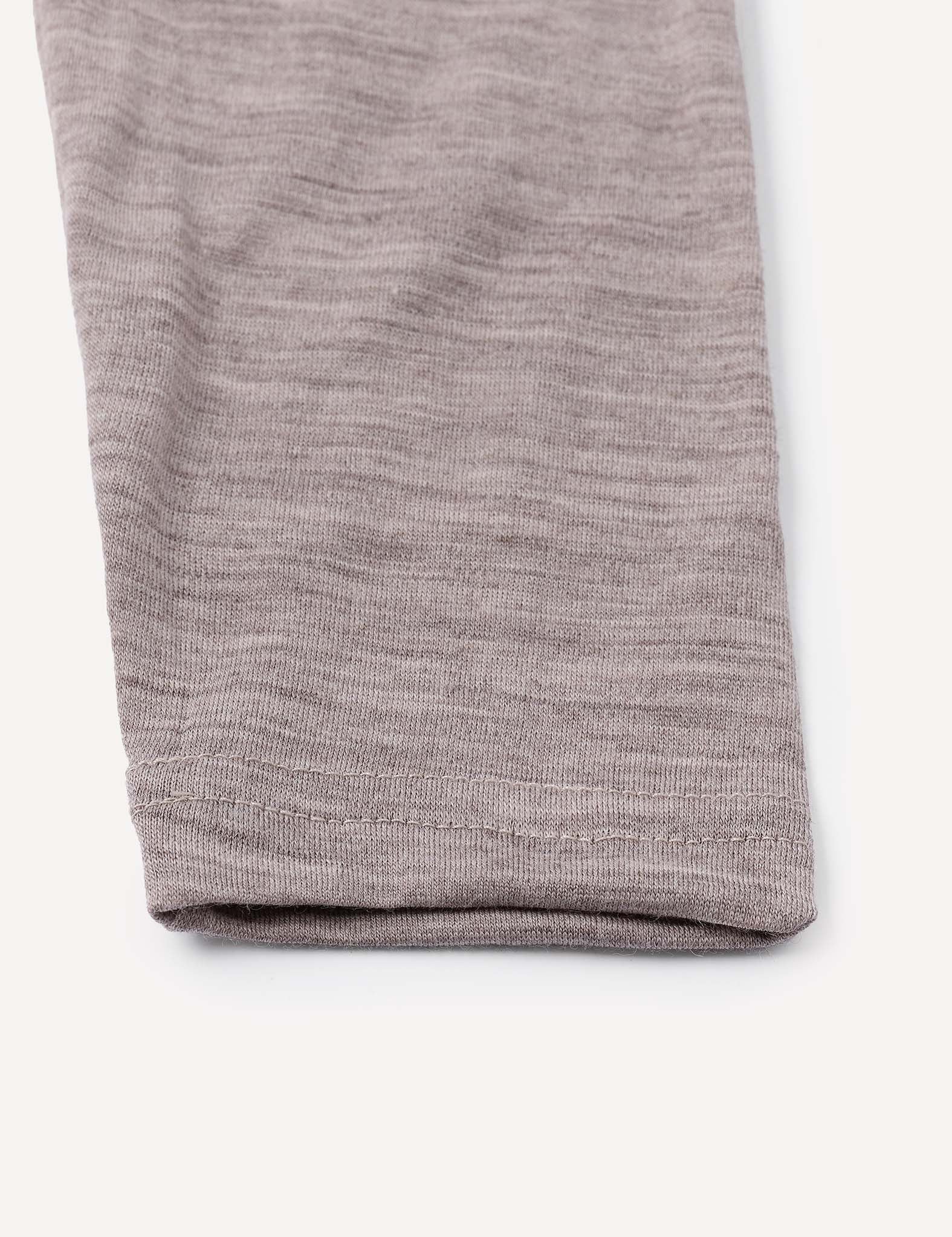Close-up of the hem of a light gray, soft knit fabric pant leg from the Leggings – Merino Baby Light, laid flat on a white background.