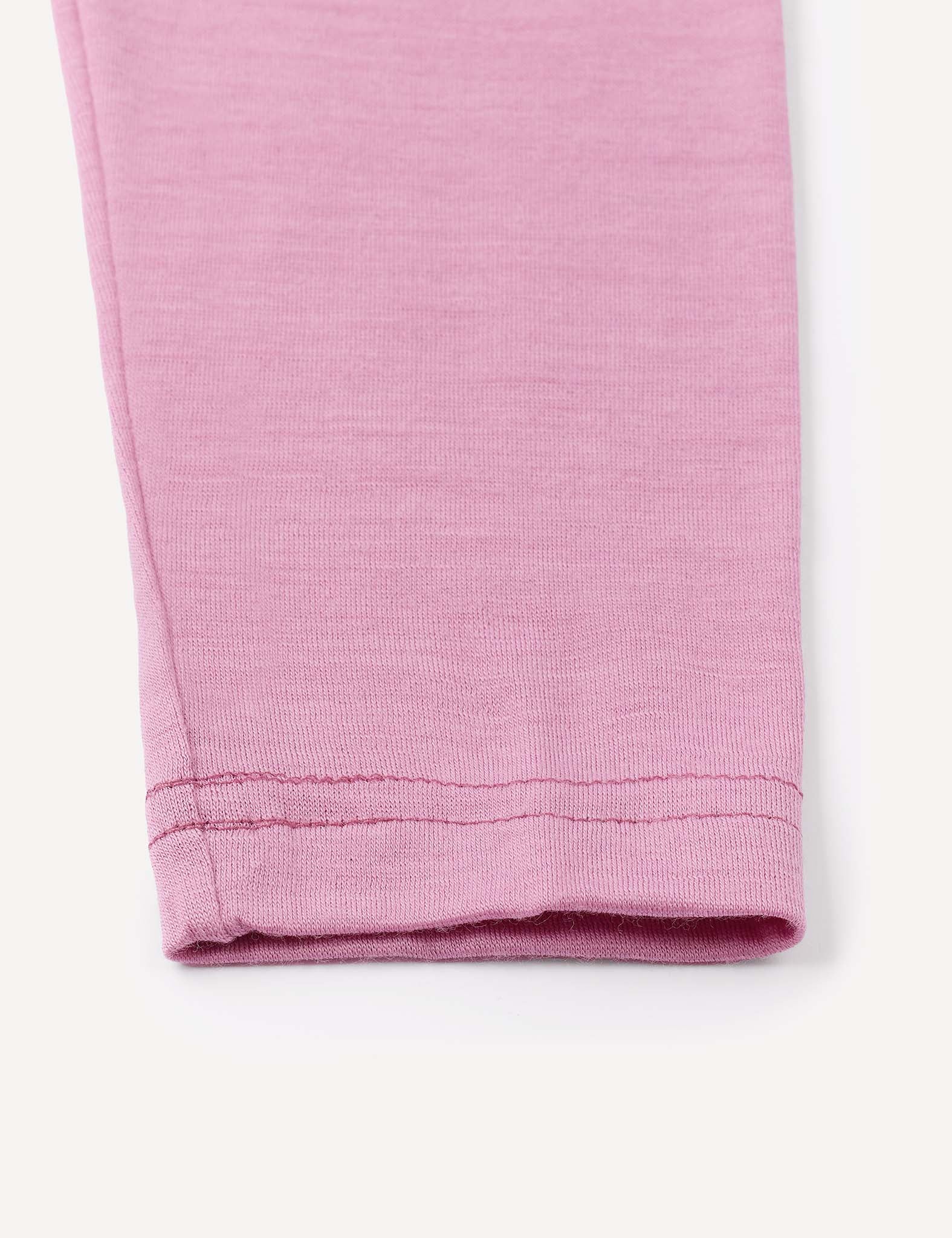 Close-up of the hem of a pink Leggings – Merino Baby Light, highlighting precise stitching details on a light background—ideal as a base layer essential for babies.