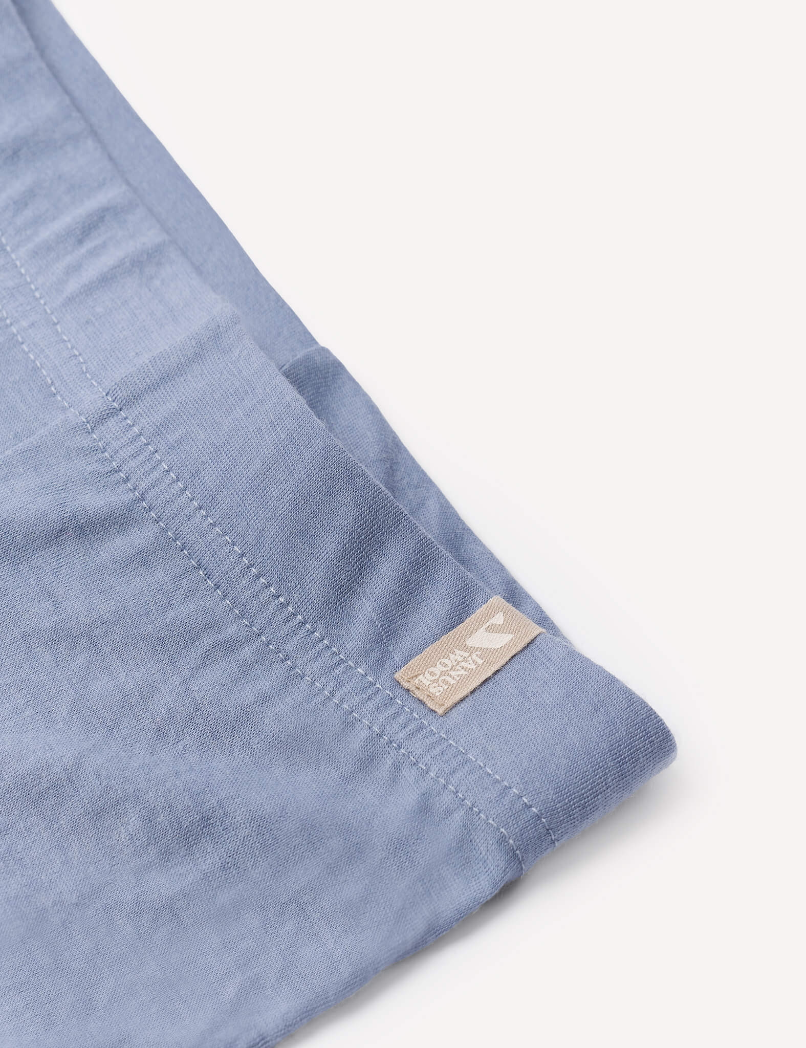 A close-up of the Leggings – Merino Baby Light in light blue fabric shows a visible seam and a small beige tag, making them ideal as a lightweight base layer or for breathable comfort.