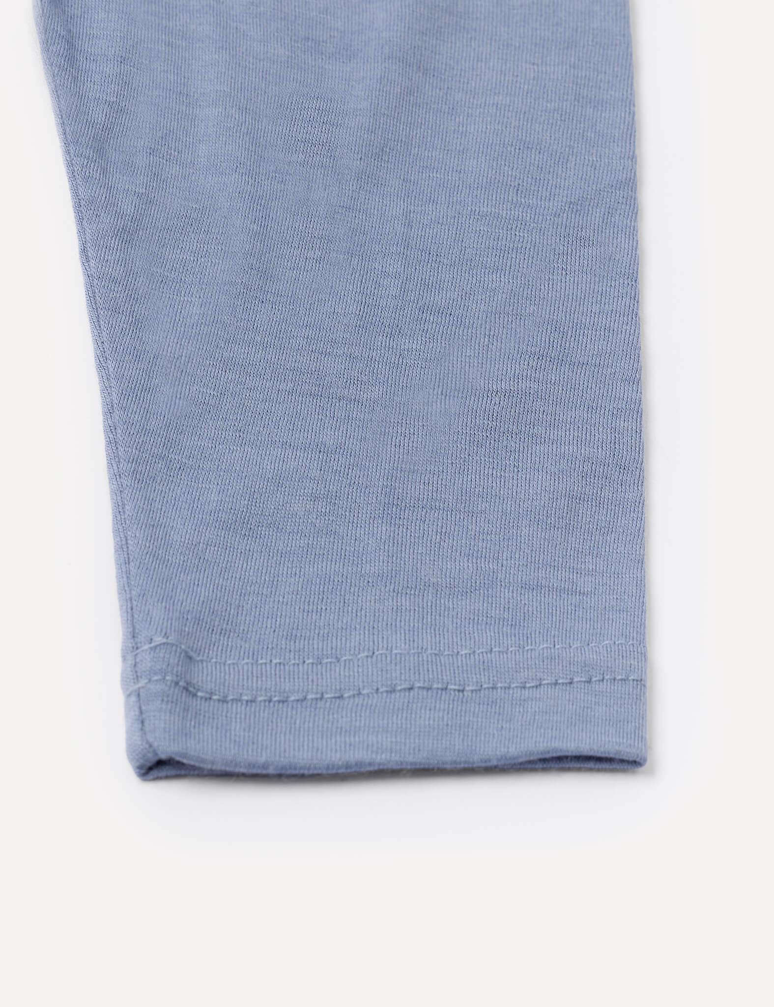 Close-up of the hem of a light blue Merino Baby Light legging, highlighting precise stitching details on a plain white background—perfect as a lightweight base layer or paired with breathable leggings.