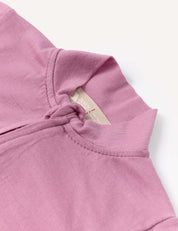 A close-up of the Pyjamas – Merino Baby Light in light purple, featuring a fabric knot at the neckline and a beige tag with text inside the collar. Crafted from breathable pyjamas material, the shirt is laid flat on a white background.