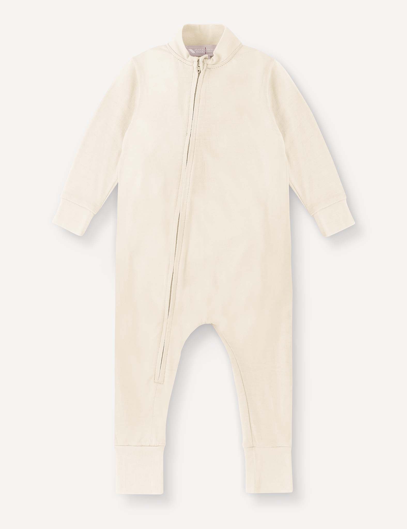 The Pyjamas – Merino Baby Light in Marshmallow is a breathable, cream-colored baby onesie designed for ultimate comfort, featuring long sleeves and legs, ribbed cuffs, and an asymmetrical front zipper running from the neck down to the left leg.