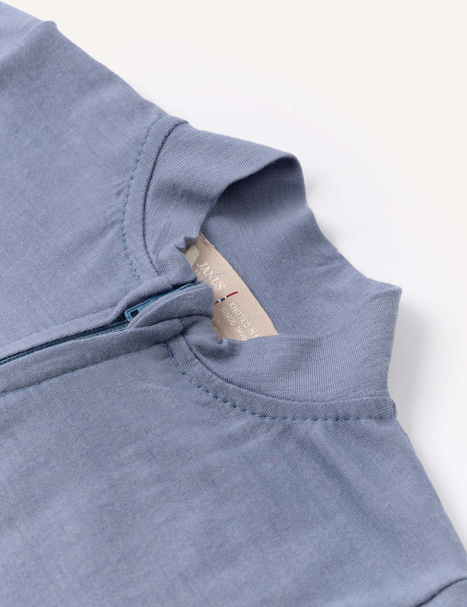 Close-up of the Pyjamas – Merino Baby Light in light blue, featuring the collar, top of the zipper, and a glimpse of a beige inner tag at the neckline. Made from soft merino wool, these pyjamas are breathable and moisture-wicking for lasting comfort all night.