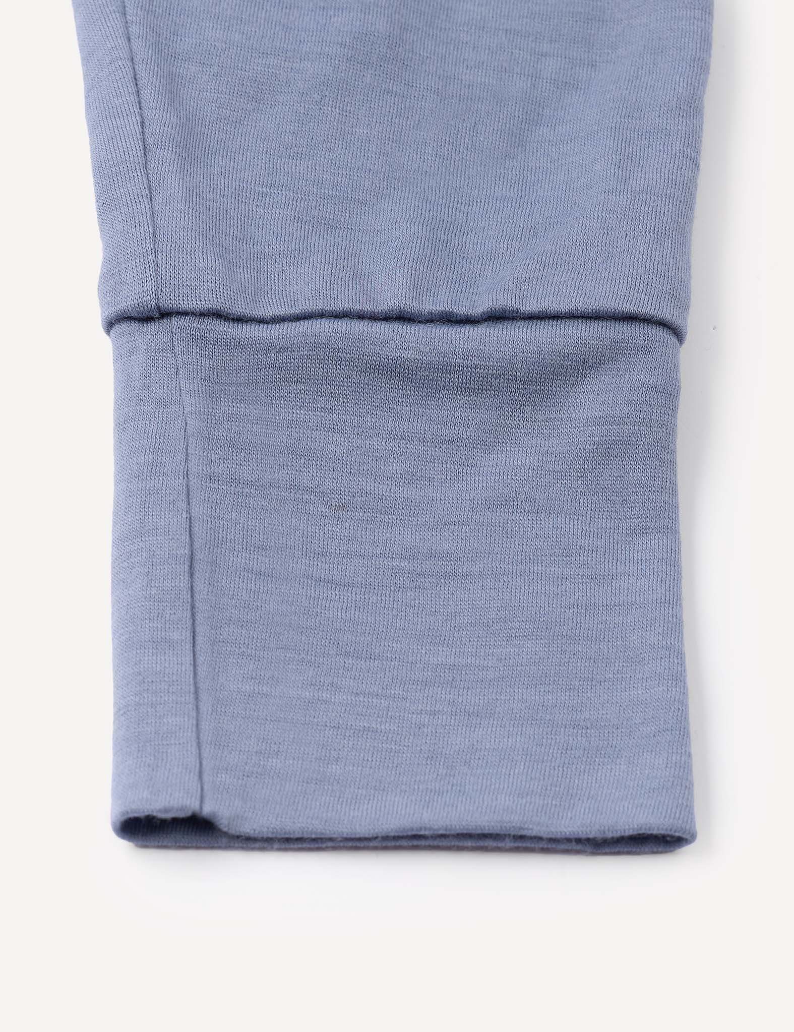 A close-up of the blue cuff from the Pyjamas – Merino Baby Light, showcasing detailed stitching and a neatly folded hem characteristic of these breathable pyjamas.
