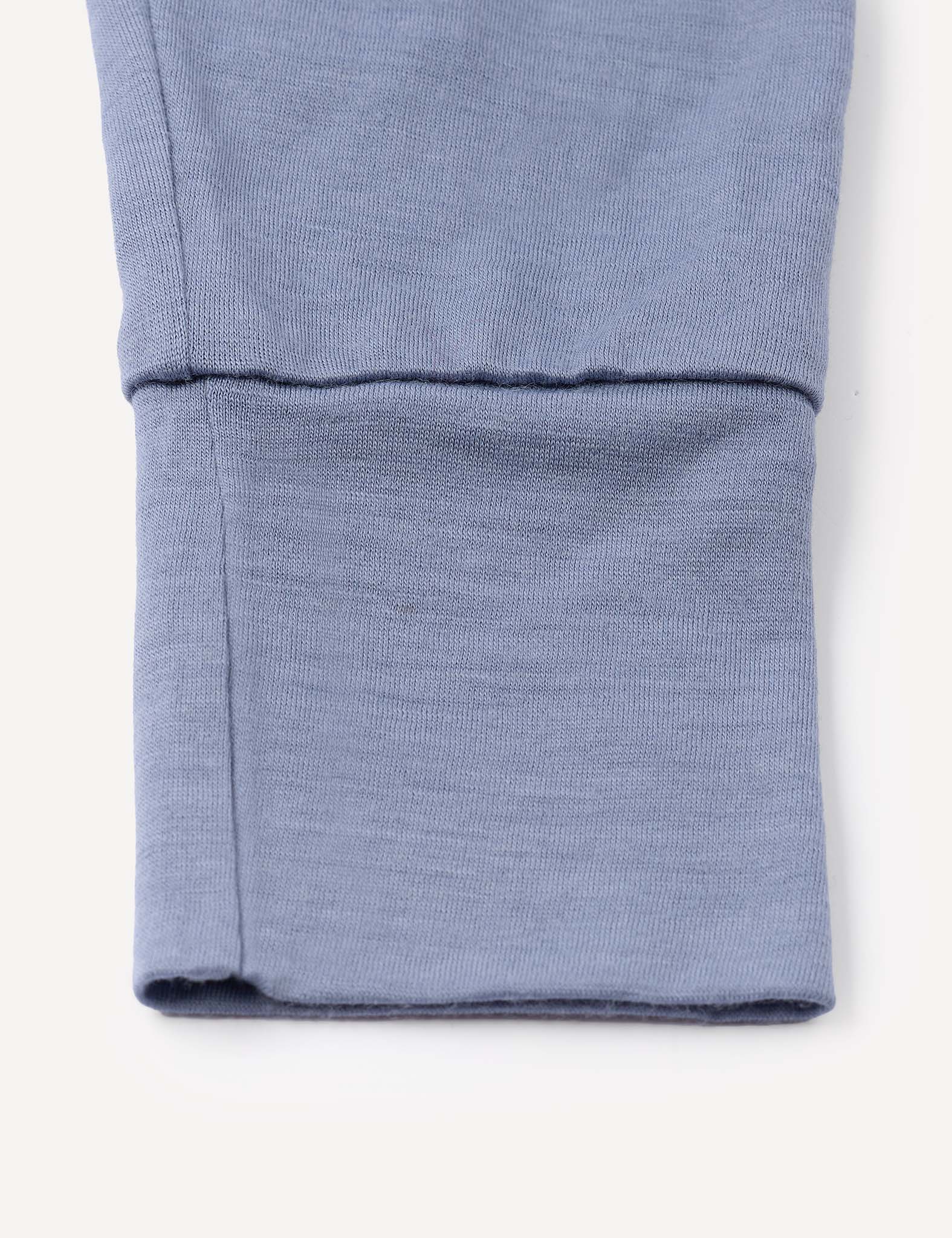A close-up of the blue cuff from the Pyjamas – Merino Baby Light, showcasing detailed stitching and a neatly folded hem characteristic of these breathable pyjamas.