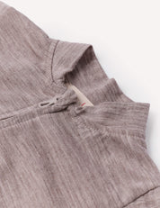 Close-up of the Pyjamas – Merino Baby Light in light brown, highlighting the collar, part of the shoulder seam, and a small fabric loop near the neckline against a plain white background—an ideal example of breathable sleepwear.