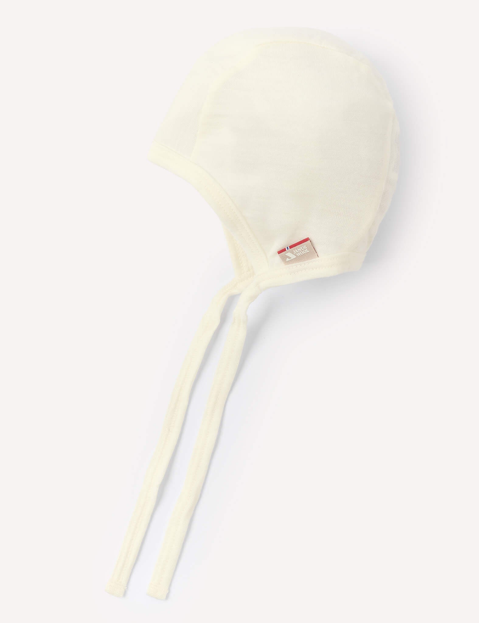 A lightweight Marshmallow-colored Bonnet – Merino Baby Light is displayed against a light background. Made from soft merino wool, this bonnet features long ties and a small red and white tag, offering a breathable and comfortable option for your baby.
