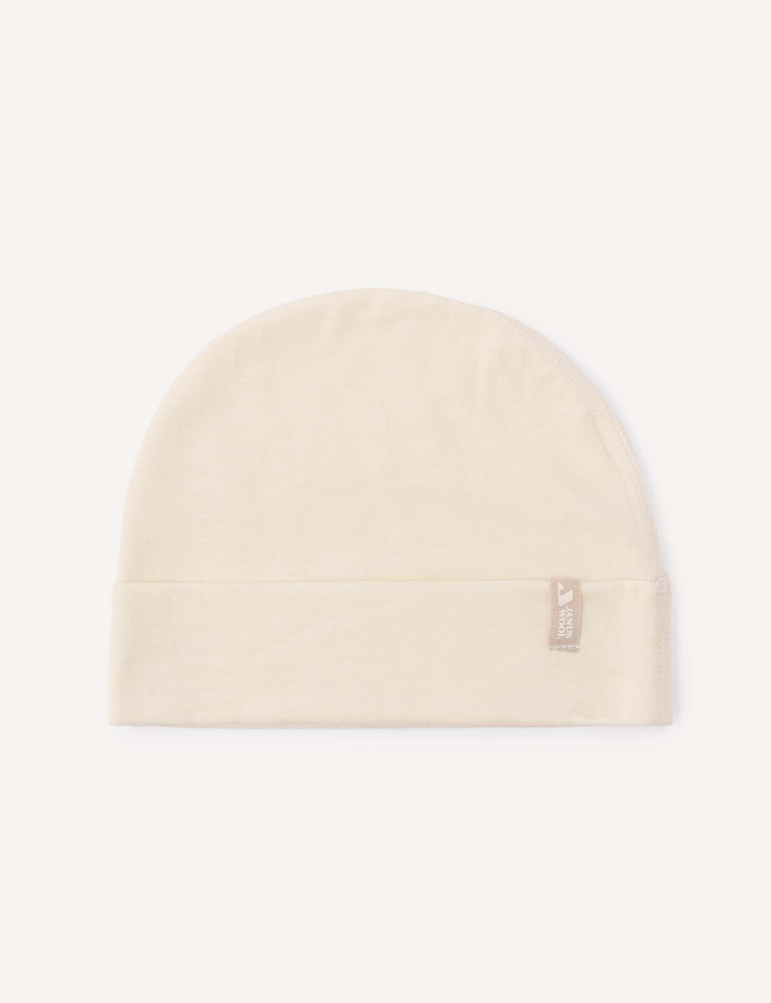 A Beanie – Merino Baby Light in the color Marshmallow, featuring a folded brim and a small fabric tag on the side, is displayed on a light background.