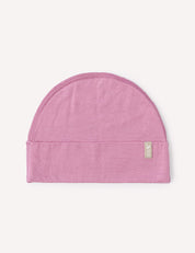 A mauve orchid, semi-circular lightweight Merino baby beanie with a folded brim and a small rectangular tag on the right side, displayed on a plain light background.
