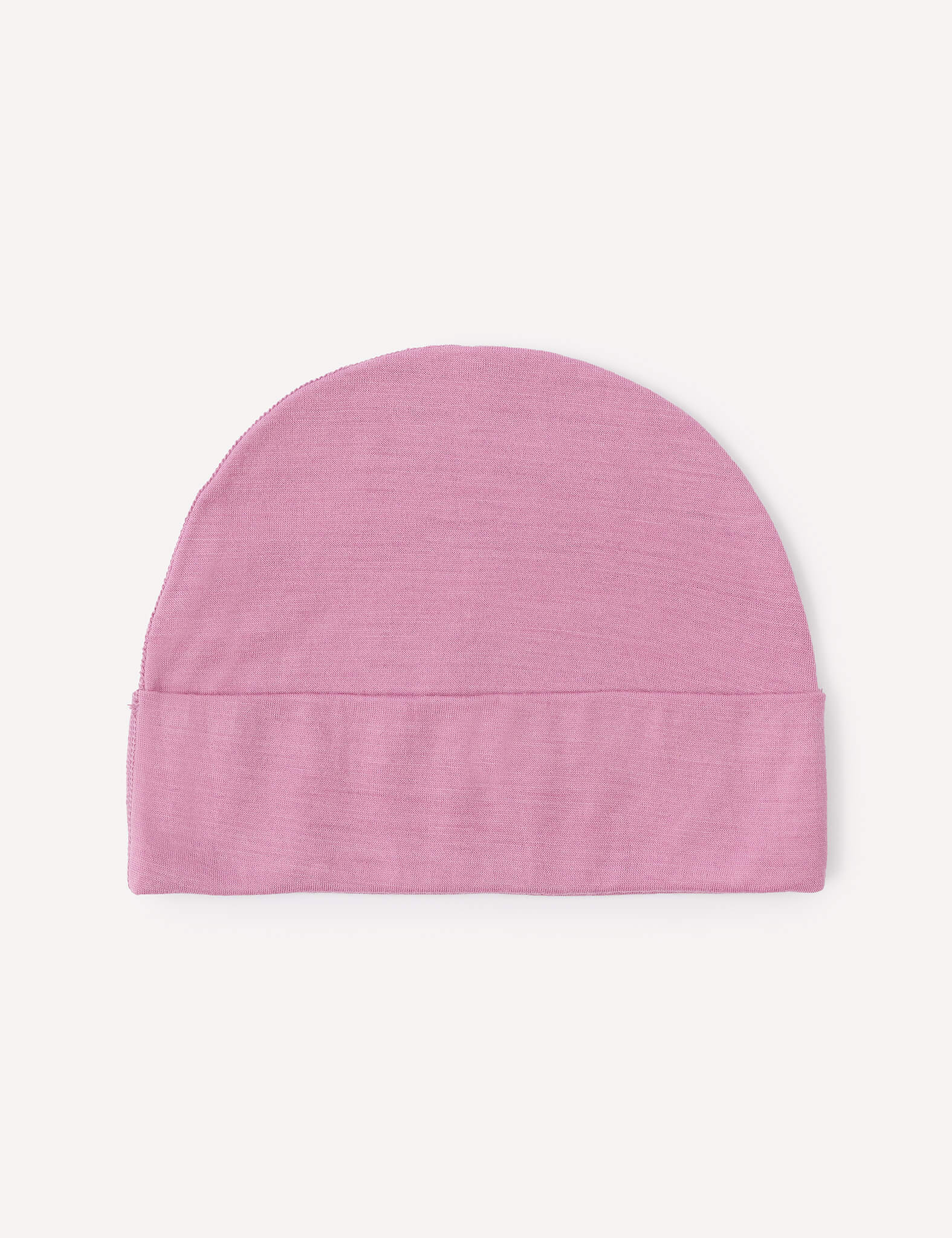 A lightweight Merino Baby Light Beanie in light pink, featuring a simple design with a folded brim, is laid flat on a plain white background.