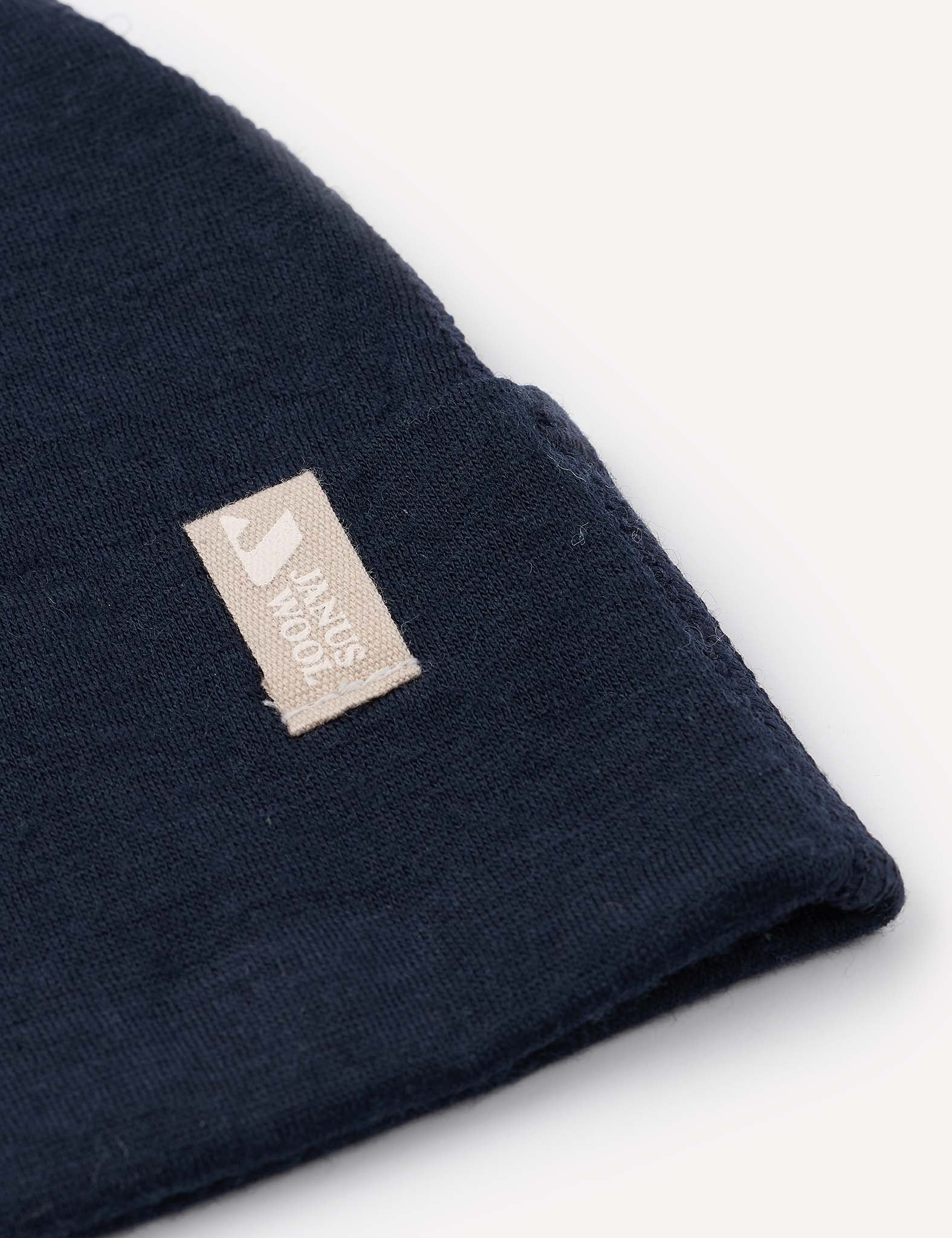 A close-up of the Beanie – Merino Baby Light in dark blue, featuring a beige fabric tag with “Hands Tools” in white text, displayed against a plain, light background.