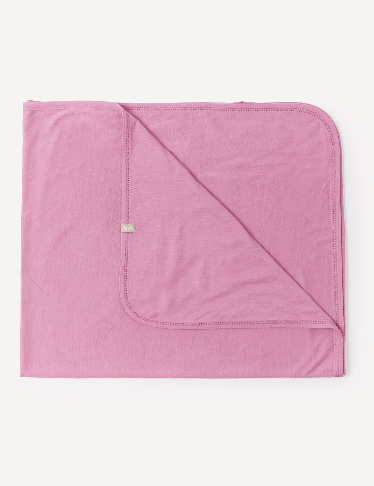 A neatly folded Blanket – Merino Baby Light in Mauve Orchid, featuring lightweight fabric, rounded corners, and visible stitching, displayed on a white background.
