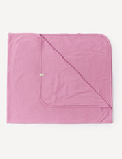 A neatly folded Blanket – Merino Baby Light in Mauve Orchid, featuring lightweight fabric, rounded corners, and visible stitching, displayed on a white background.