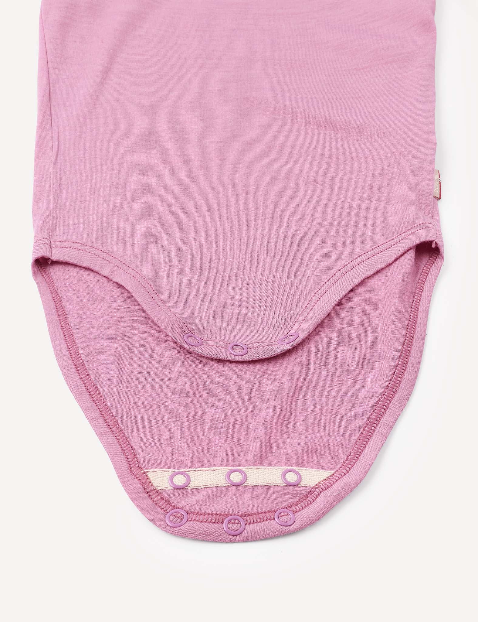 A close-up of the Body – Merino Baby Light in light purple shows the bottom with snap button closures open, revealing the soft merino inner fabric. This breathable baby bodysuit offers comfort and practicality for little ones.