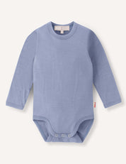 A long-sleeve baby bodysuit in the color Troposphere (light blue), named Body – Merino Baby Light, featuring snap buttons at the bottom. Displayed on a plain white background, this breathable merino baby clothing provides comfort and style for little ones.