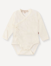 Wrapover Bodysuit – Merino Baby Light in Marshmallow, featuring long sleeves, a side tie, and snap buttons at the bottom, laid flat on a white background.