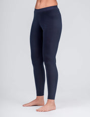 A person stands barefoot against a light gray background, wearing high-waisted, full-length Classic Merino 160 Women Leggings in Navy, made from breathable, temperature-regulating merino fabric.