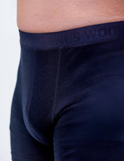 Close-up of a person wearing Boxers – Classic Merino 160 Men in dark blue, showing the embossed waistband. The image highlights the waist and upper thigh, emphasizing comfortable, breathable, and temperature-regulating merino underwear.