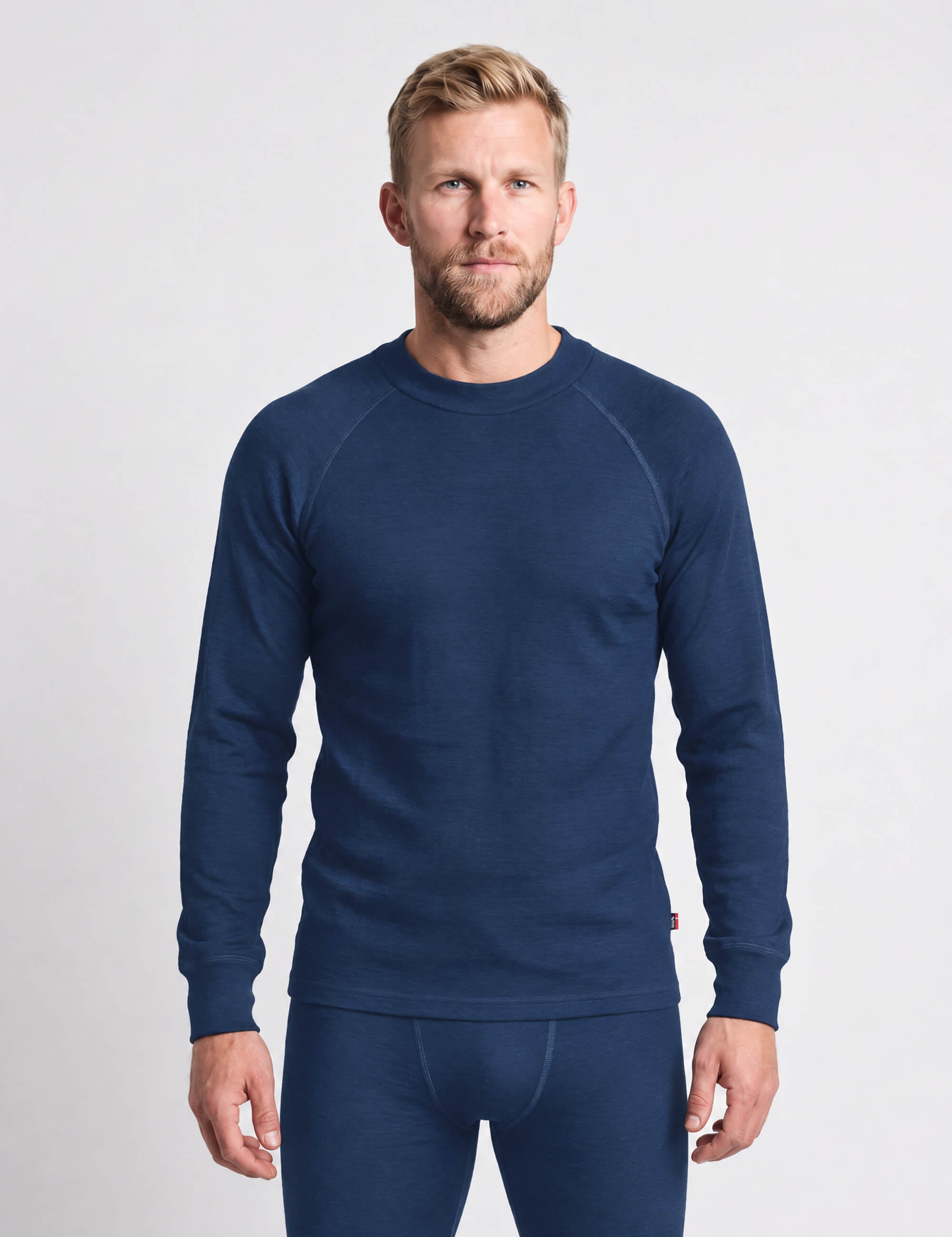 A man wearing a blue Wool Set – Classic Merino 200 Rib Men long-sleeved crew-neck shirt and matching base layer pants.
