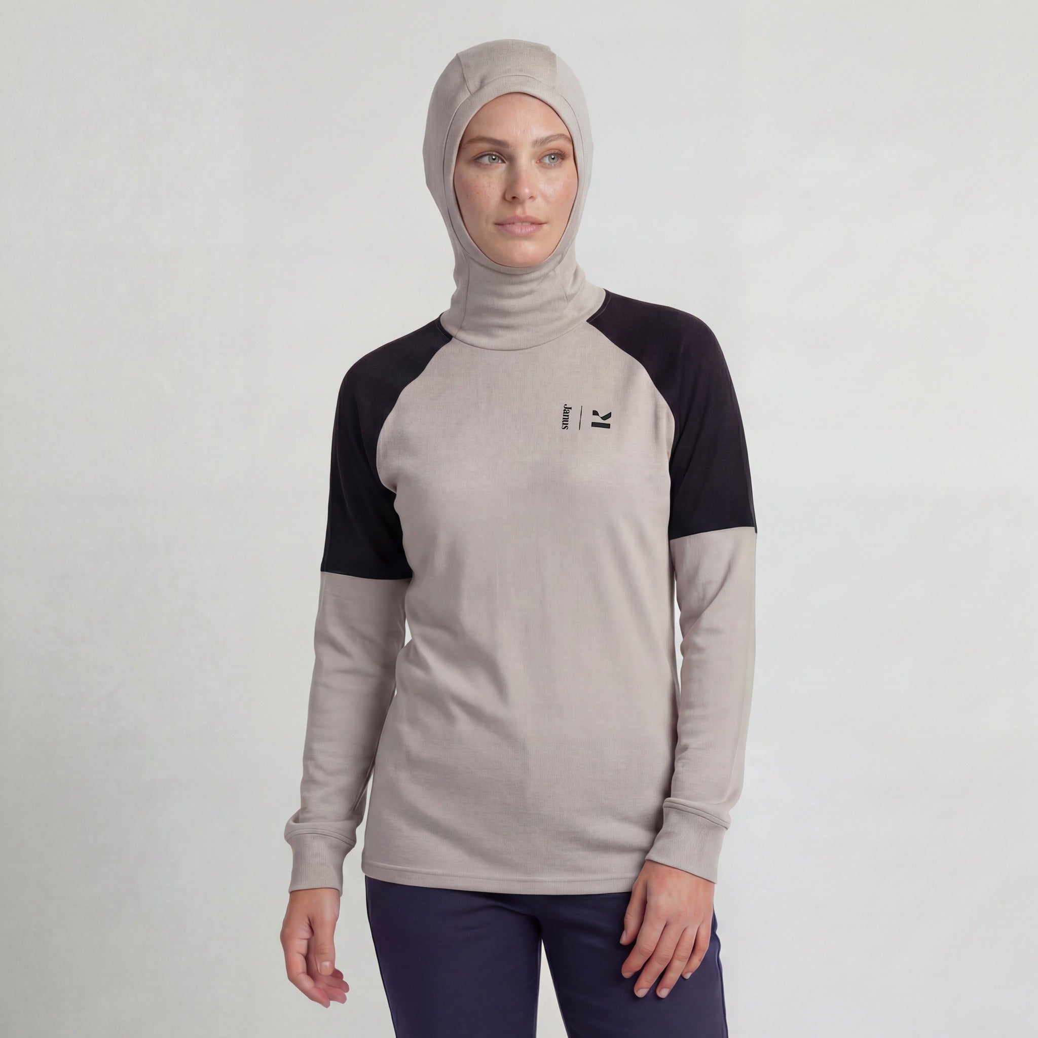 A woman wearing the beige Hooded jersey merino - Kleveland 215 stands against a plain light background, looking slightly to the side with a neutral expression.