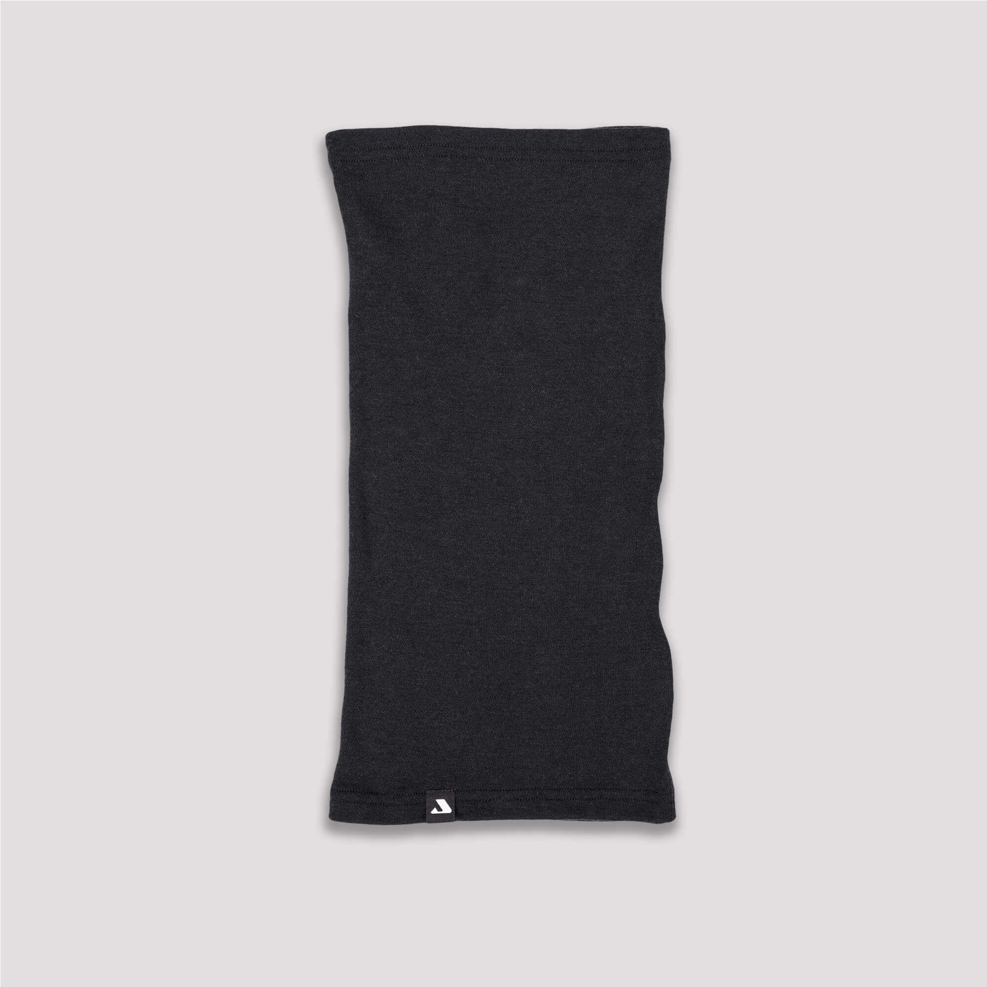 The Neck Warmer – Classic Merino 215 in black is shown laid flat on a light background, with a small white tag at the bottom edge, designed for warmth and breathability.