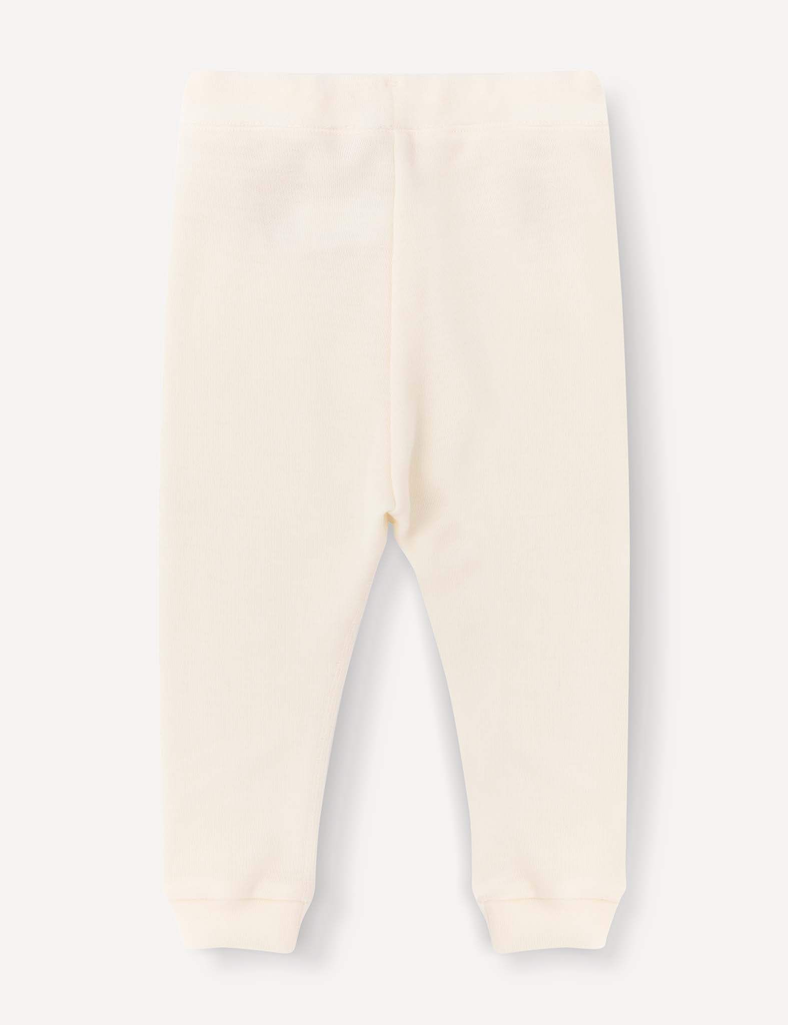 Cream-colored Merino Baby AirWool pants for babies or toddlers, featuring an elastic waistband and cuffed ankles, laid flat on a light background and displayed from the back for a relaxed fit.