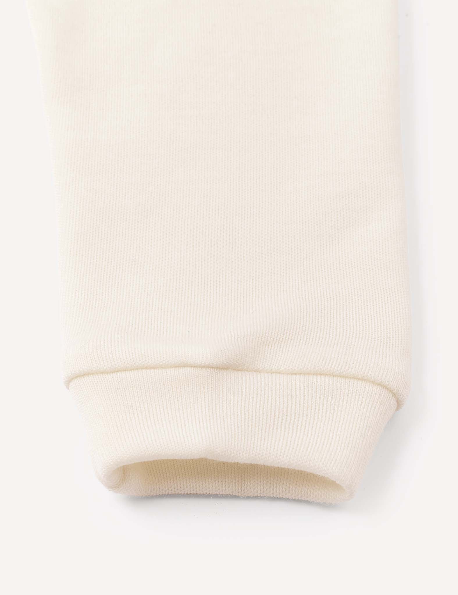 Close-up of the cuff of a cream-colored, ribbed fabric leg, likely from the Merino Baby AirWool pants, against a plain background.