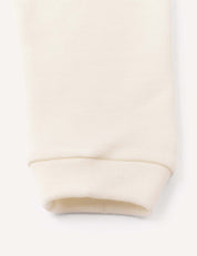 Close-up of the cuff of a cream-colored, ribbed fabric leg, likely from the Merino Baby AirWool pants, against a plain background.