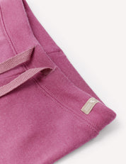 Close-up of the Pants – Merino Baby AirWool in pink, showcasing an adjustable drawcord and a small beige tag with logo and text on the waistband, set against a white background.