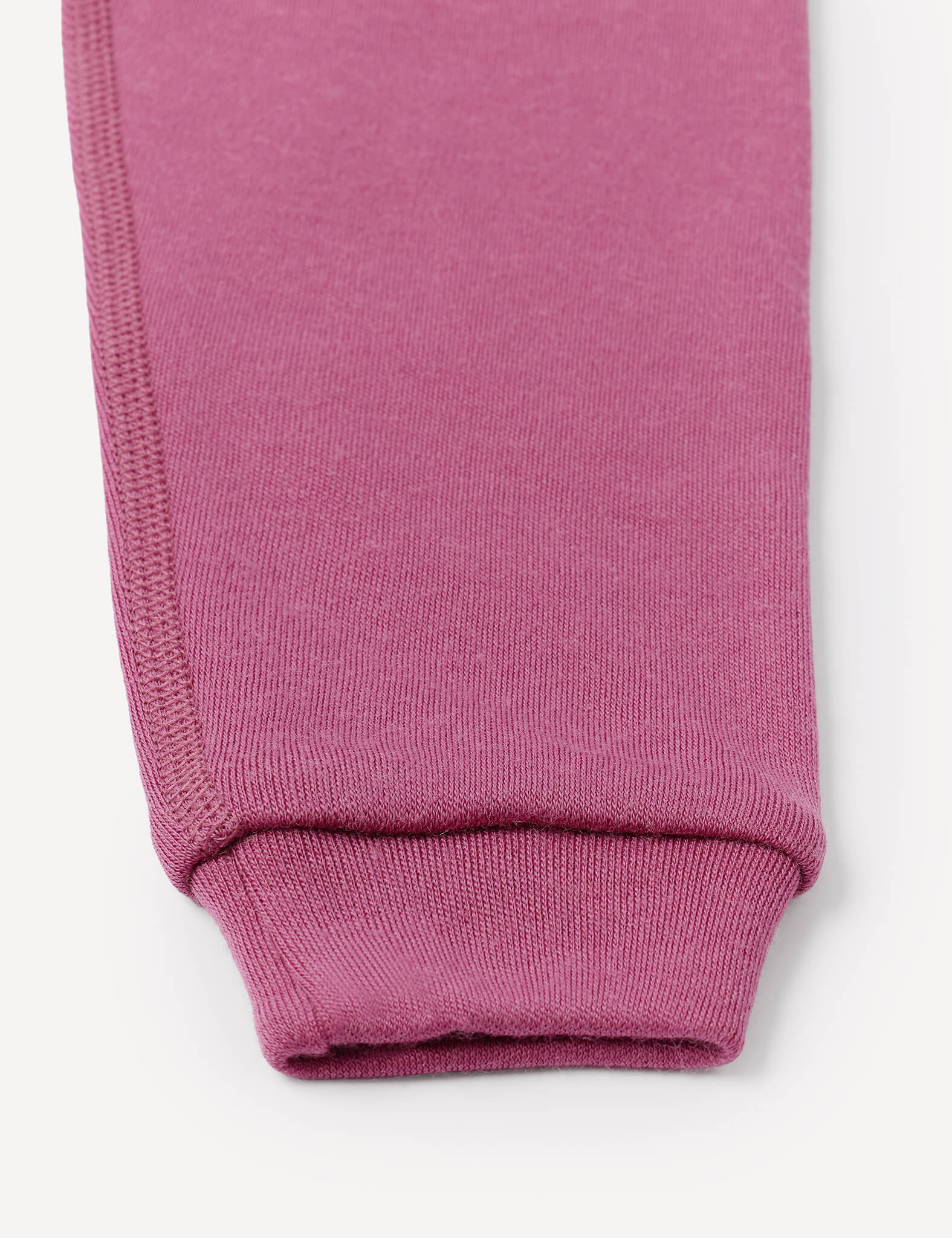 Close-up of the cuff of a pink or mauve knit sleeve, highlighting the seam and ribbed texture against a white background, paired with relaxed fit Pants – Merino Baby AirWool for a comfortable and stylish look.