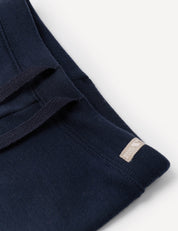 Close-up of the Pants – Merino Baby AirWool in navy blue, featuring an adjustable drawcord and a small beige tag on the seam, shown against a white background.