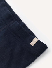 Close-up of a navy blue fabric with visible stitching and a small beige tag that reads KNOWN SUPPLY sewn on the edge, highlighting details characteristic of the Leggings – Merino Baby AirWool.