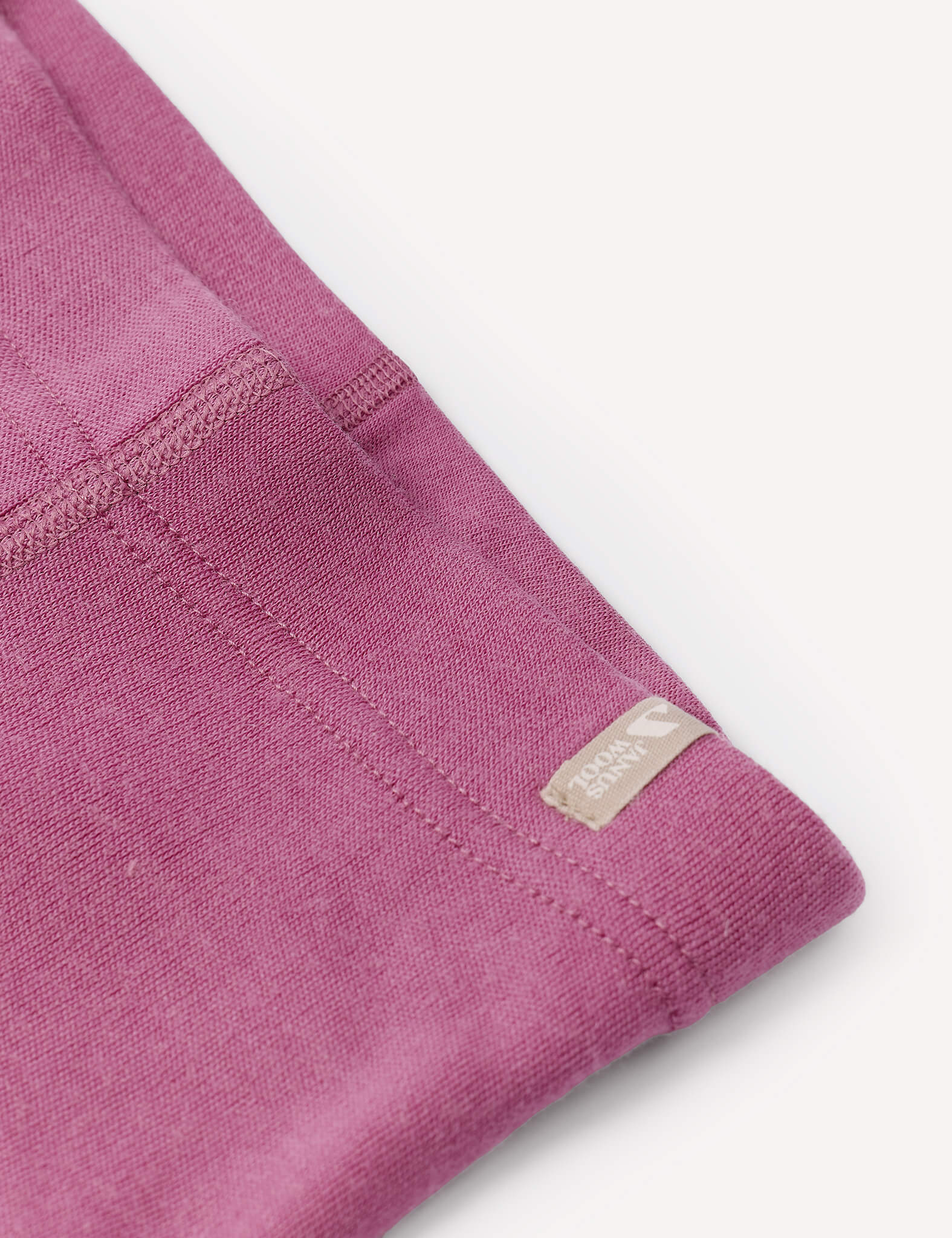 Close-up of a folded purple Leggings – Merino Baby AirWool garment with visible stitching and a small beige tag that reads Carhartt near the seam, showcasing the warmth and softness characteristic of merino wool.
