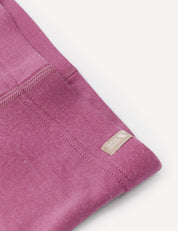 Close-up of a folded purple Leggings – Merino Baby AirWool garment with visible stitching and a small beige tag that reads Carhartt near the seam, showcasing the warmth and softness characteristic of merino wool.