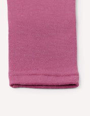 Close-up of the hem of a pink knit fabric sleeve or pant leg, likely from the Leggings – Merino Baby AirWool, highlighting the texture and stitching details against a white background.