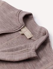 Close-up of the Onesie – Merino Baby AirWool in light brown, highlighting the collar and inner stitching details, with a beige fabric tag inside the neckline. The onesie features fold-over cuffs for added style and functionality.