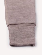 Close-up of the cuff of the Onesie – Merino Baby AirWool, featuring light brown, ribbed fabric with fold-over cuffs, shown against a plain white background.