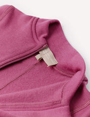Close-up of the Onesie – Merino Baby AirWool in mauve, highlighting the neckline and inner tag, which is beige with text. The image showcases the fabric texture and stitching details, as well as fold-over cuffs designed for added comfort.