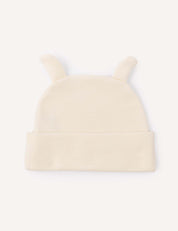 A cream-colored Beanie – Merino Baby AirWool, featuring two small fabric ears on top and crafted from breathable merino wool for gentle insulation, displayed on a plain white background.
