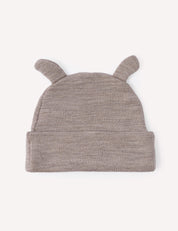 The Beanie – Merino Baby AirWool is a soft, light brown knit baby beanie crafted from gentle AirWool, featuring two small, rounded ear-like protrusions on top and shown laid flat on a light background.