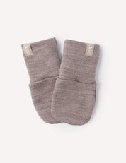 A pair of Beige Melange Mittens – Merino Baby AirWool, crafted from soft merino wool with a knit texture, featuring folded cuffs and small cream-colored fabric tags on each cuff, are positioned side by side on a plain white background.